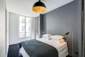 Quarto moderno com uma cama grande, um abajur e uma janela com cortinas.