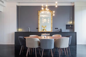 A modern kitchen with a central island, a large mirror, and a dining area with chairs.