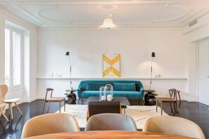 A modern living room with a teal sofa, a wooden coffee table, and a chandelier.