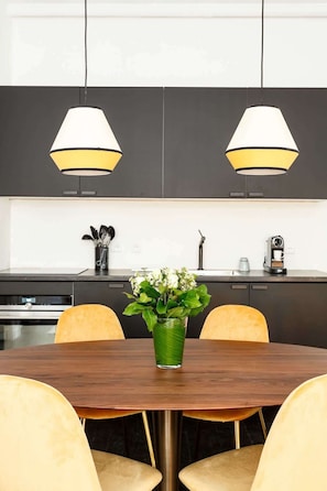 Uma cozinha moderna com duas luminárias pendentes, uma mesa de jantar com cadeiras e um vaso com flores.