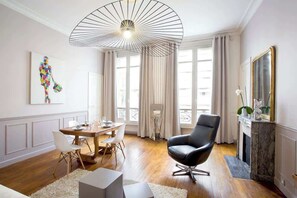Uma sala de estar moderna com área de jantar, lareira e uma janela grande com cortinas.