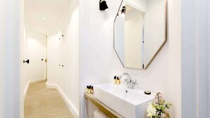 Un baño moderno con lavamanos, espejo y toallero blancos.