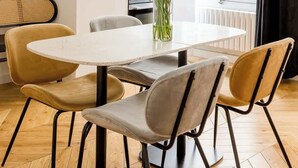 Un comedor moderno con una mesa redonda, cuatro sillas y un jarrón con flores.
