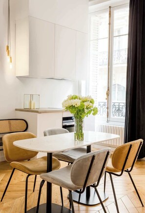 Een moderne eetruimte met een ronde tafel, vier stoelen en een bloevas.