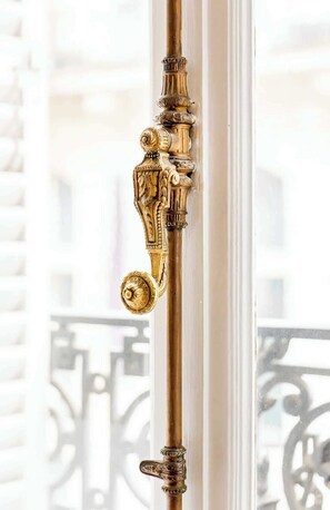 A brass door handle with intricate designs, attached to a white door frame.