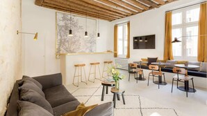 En moderne stue med sofa, spiseplads og store vinduer.