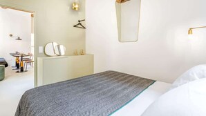 Et moderne hotelværelse med seng, kommode, spejl og skrivebord med stole.
