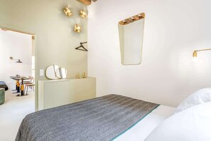 Une chambre d’hôtel moderne équipée d’un lit, d’une commode, d’un miroir et d’un bureau avec des chaises.