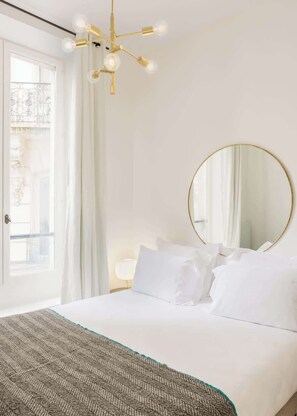 A hotel room with a bed, a round mirror, and a chandelier. - Cosy apartment in Sentier village - 1 bedroom - Steps from Montorgueil market - Montmartre by Habitat Parisien (Paris)