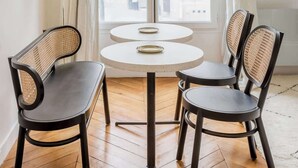 A room with a round table and two chairs, a floor lamp, and a window with curtains.