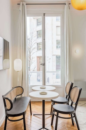 Une pièce avec une table ronde et deux chaises, un lampadaire et une fenêtre avec des rideaux.