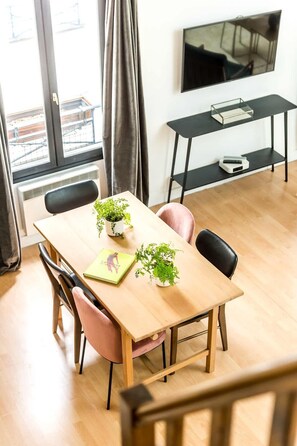Quarto moderno com mesa de madeira, cadeiras e plantas em vasos.