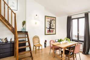 A dining area with a wooden table, chairs, and a poster on the wall.