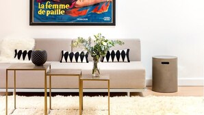 A living room with a sofa, a coffee table, and a framed movie poster on the wall.