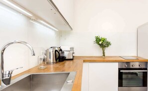 A modern kitchen with stainless steel appliances, a wooden countertop, and a small potted plant.