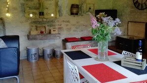 Comedor rústico con una mesa blanca y manteles a cuadros rojos y negros, un florero y una lámpara esférica colgante.