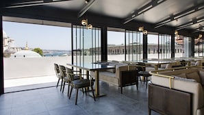A rooftop bar with a glass table, chairs, and sofas, offering a view of the cityscape. - Mest Hotel Istanbul Sirkeci (Istanbul)