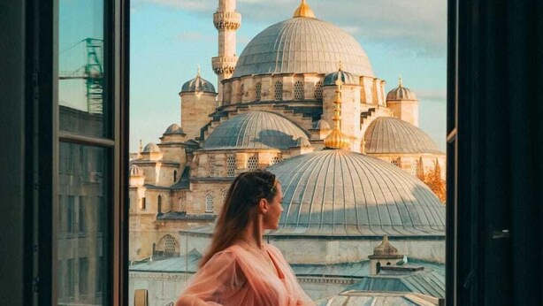 A room with a large window offering a view of a historic building with multiple domes and a minaret. - Mest Hotel Istanbul Sirkeci (Istanbul)
