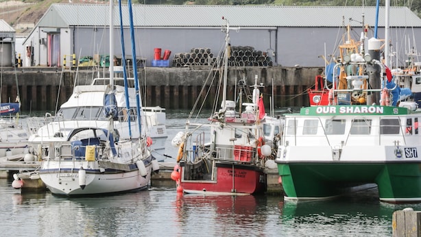 Un port de plaisance où sont amarrés plusieurs bateaux, dont un bateau vert baptisé « OUR SHARON ».