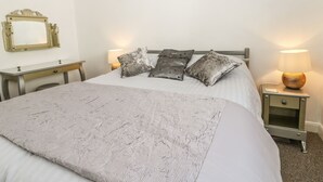 Une chambre à coucher bien rangée, avec un lit, des tables de chevet, un bureau et un miroir.