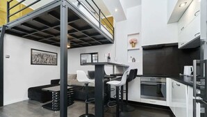 Una cocina moderna con entrepiso, taburetes de bar y comedor.