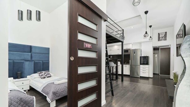 Una habitación de hotel moderna con una cama grande, un escritorio y una kitchenette.