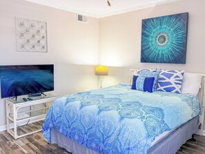 A bedroom with a bed, a TV, and artwork on the walls. - Ocean Shores 301 (North Myrtle Beach)