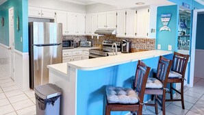 Una cocina moderna con armarios blancos, electrodomésticos de acero inoxidable y una pared de acento azul.