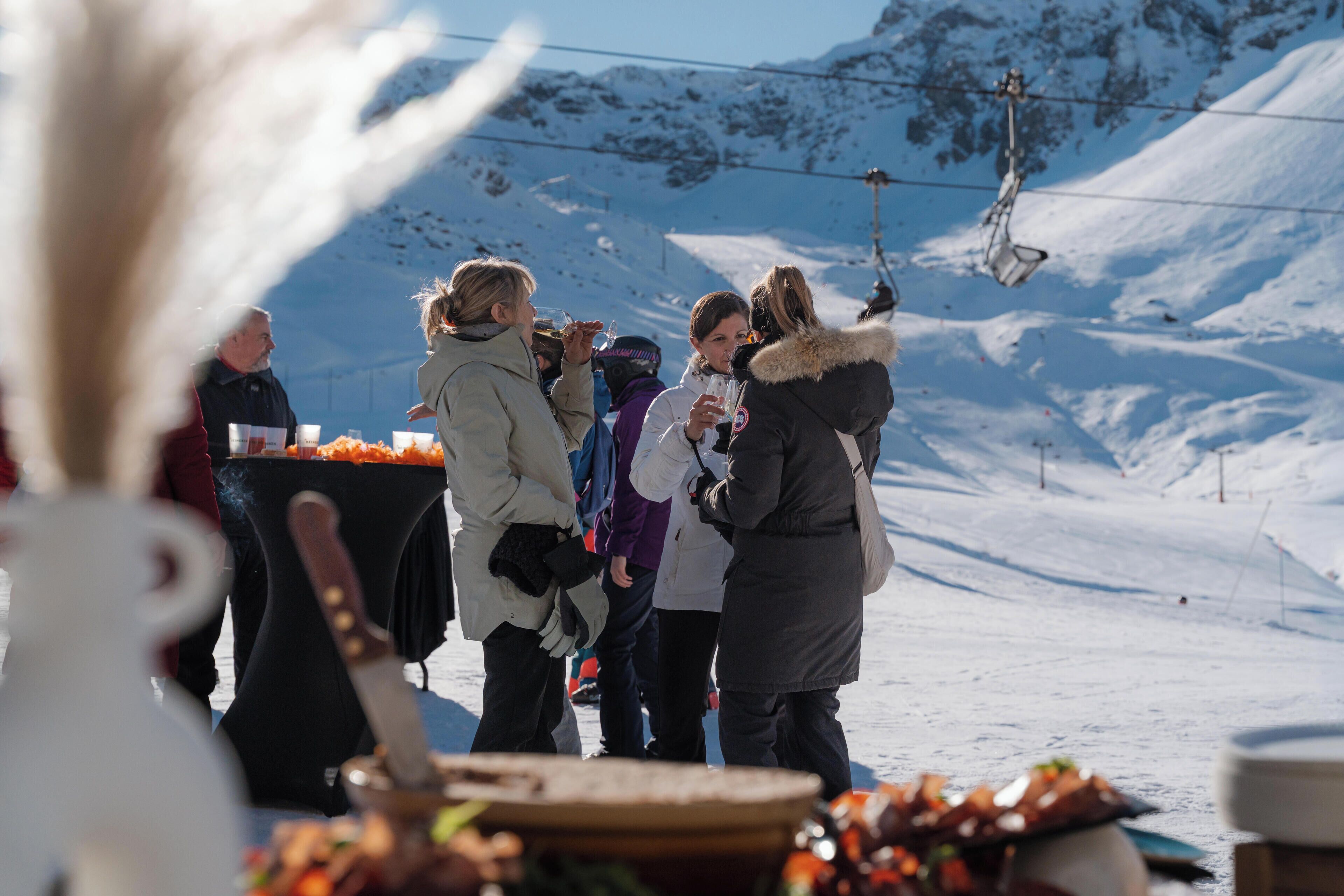 A group of people standing outdoors in a snowy environment with a ski lift in the background.