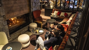 A cozy lounge area with a stone fireplace, comfortable seating, and a view of the dining area. - Belambra Clubs Tignes - Val Claret (Tignes)