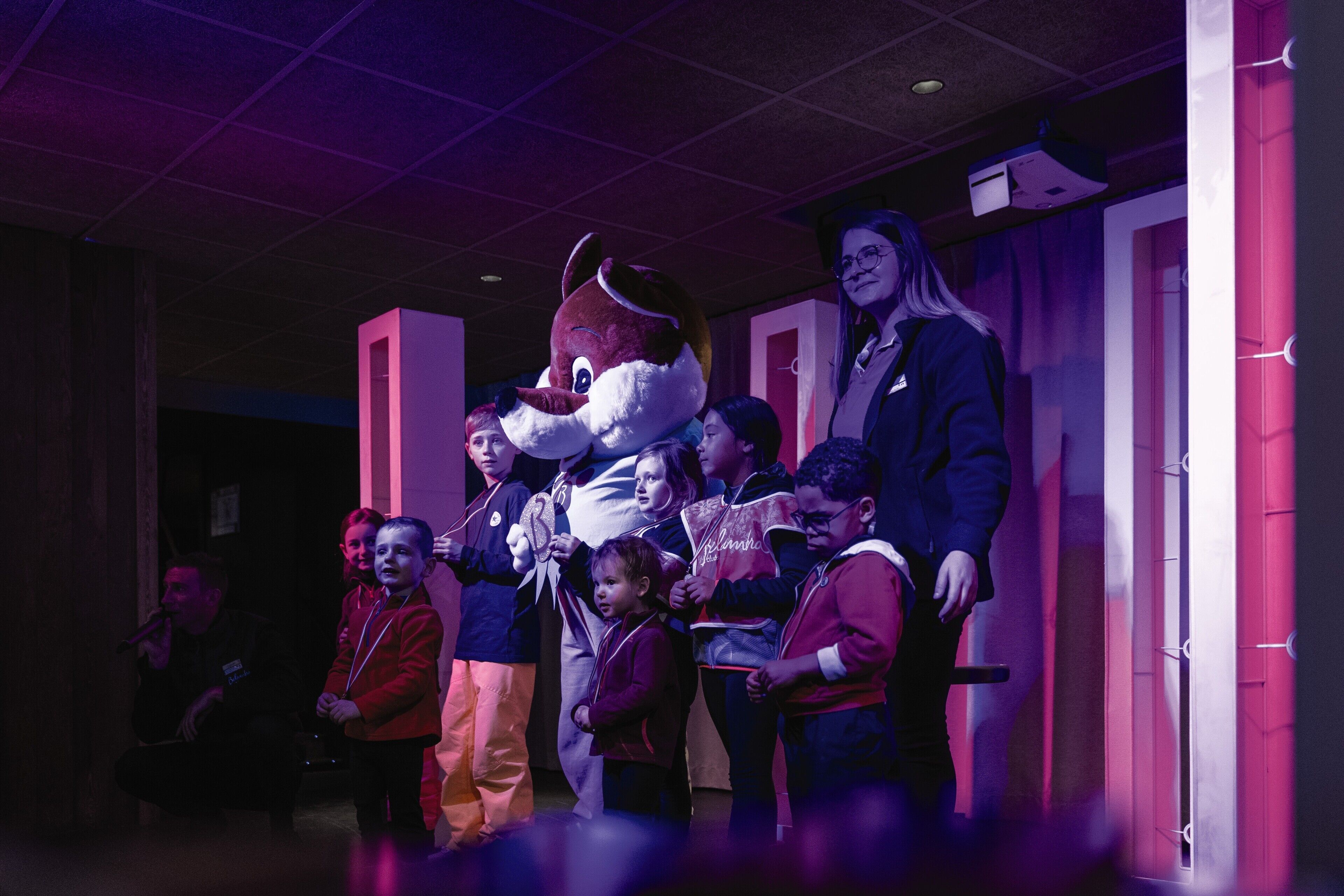 A group of people in a hallway with a large mascot figure.