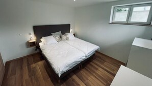 A bedroom with a bed, wooden flooring, a nightstand, and a window. - RANDOM LISTING (Wintzenheim)
