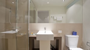 A modern bathroom with a glass-enclosed shower, a white sink, and a toilet. - Resort Hotel Room 261 (TORQUAY)