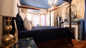 A bedroom with a four-poster bed, a chandelier, a fireplace, and a brick wall. - Immersion Experience Into a Fictional Magical World (Saint Joseph)