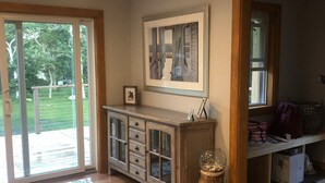 A spacious room with a wooden floor, a glass door leading to a balcony, a built-in cabinet with drawers, and a framed picture on the wall. - Centrally located in OakBluffs on Martha’s Vineyard (Oak Bluffs)