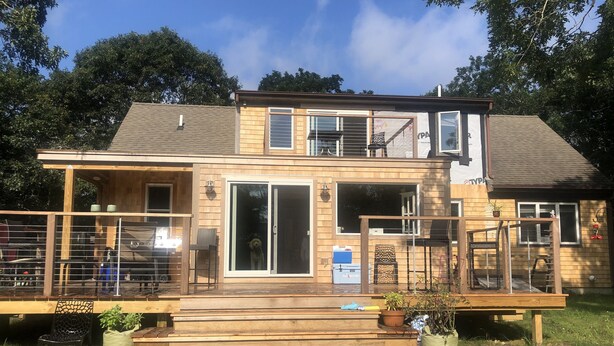 A two-story house with a deck, large sliding glass doors, and a small outdoor kitchen area. - Centrally located in OakBluffs on Martha’s Vineyard (Oak Bluffs)