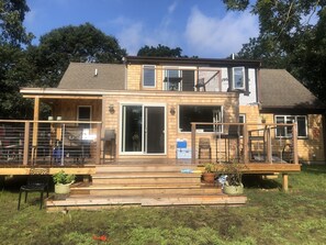 A two-story house with a deck, large sliding glass doors, and a small outdoor kitchen area. - Centrally located in OakBluffs on Martha’s Vineyard (Oak Bluffs)