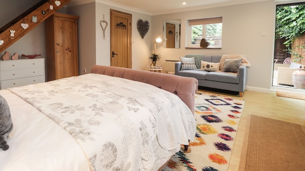 A bedroom with a bed, a sofa, a dresser, and a staircase.