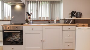 A modern kitchen with a built-in oven, a stainless steel range hood, and a coffee maker on the countertop.