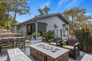 A house with a patio area featuring outdoor furniture, a fire pit, and various plants.
