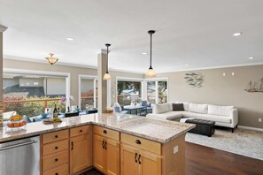 A spacious kitchen with a large island, wooden cabinets, and pendant lighting. - Shell's Treasure: Fully Updated Three bedroom home with Ocean Views (Pacific Grove)