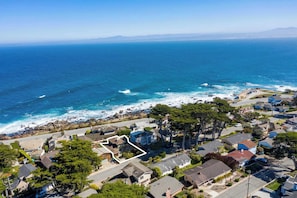 Vue aérienne d’une zone résidentielle côtière, avec des maisons, une plage et une vue sur l’océan.