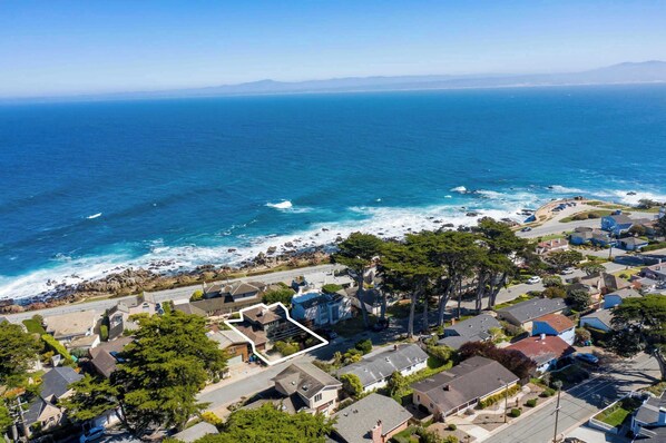 An aerial view of a coastal residential area with houses, a beach, and ocean views. - Shell's Treasure: Fully Updated Three bedroom home with Ocean Views (Pacific Grove)