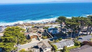 An aerial view of a coastal residential area with houses, a clear blue ocean, and a marked property. - Shell's Treasure: Fully Updated Three bedroom home with Ocean Views (Pacific Grove)