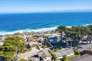An aerial view of a coastal residential area with houses, a clear blue ocean, and a marked property. - Shell's Treasure: Fully Updated Three bedroom home with Ocean Views (Pacific Grove)
