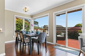 A dining area with a table set for four, a chandelier, and a view of the outdoors.