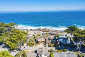 A coastal residential area with houses, trees, and a view of the ocean.