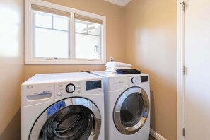A laundry area with two front-loading washing machines, a window above, and a door to the right. - Shell's Treasure: Fully Updated Three bedroom home with Ocean Views (Pacific Grove)