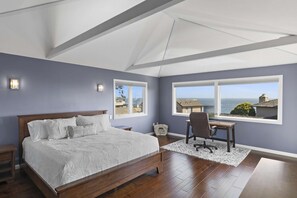 Une chambre avec un grand lit, un bureau et une vue sur l’océan.