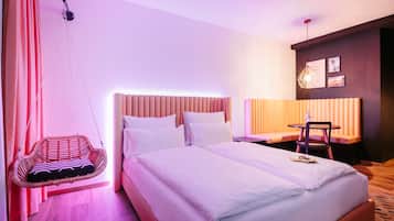 Quarto de hotel com cama grande, cadeira suspensa, escrivaninha e uma cadeira.